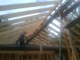 Rafters going up over a new addition with a worker on the wall in Fort Dodge