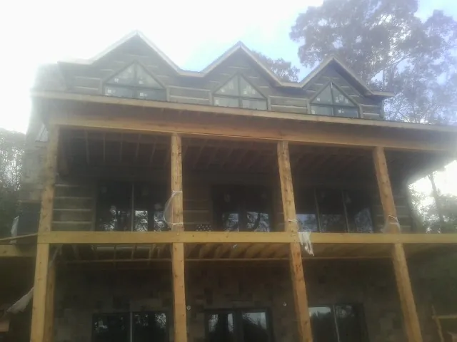 Dormers and porch framing on a large log home under construction — Roof Coating work by our crew in Fort Dodge