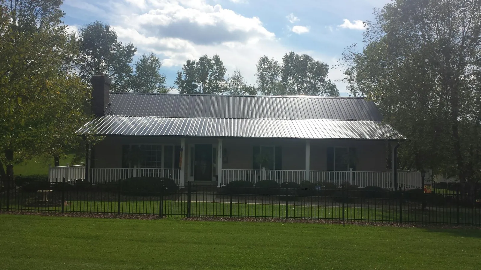 Gray metal roof on a brick ranch with a full width front porch — Gutter Guard Installation work by our crew in Fort Dodge
