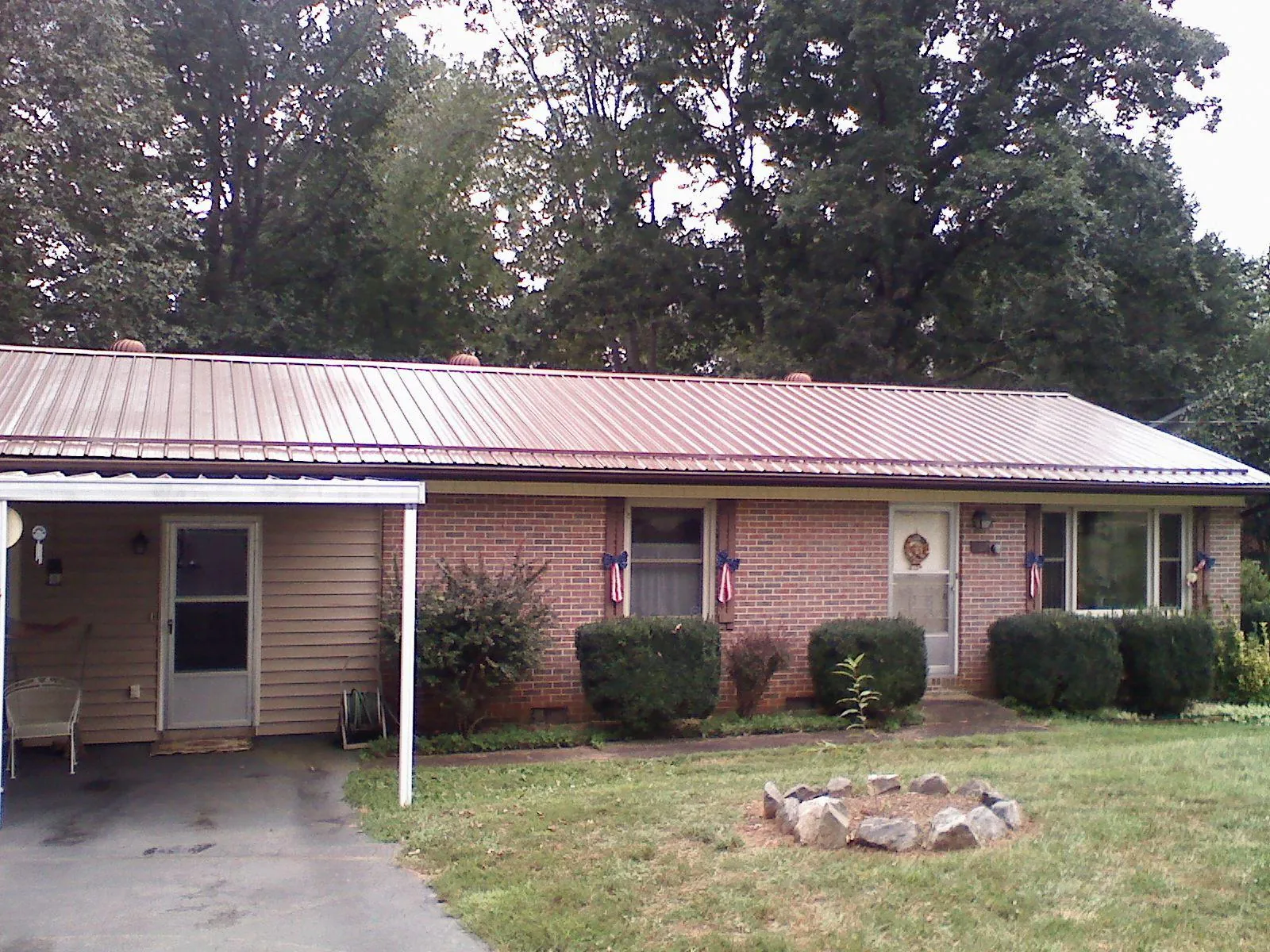Bronze metal roof and carport on a brick ranch home — Roof Repair work by our crew in Fort Dodge